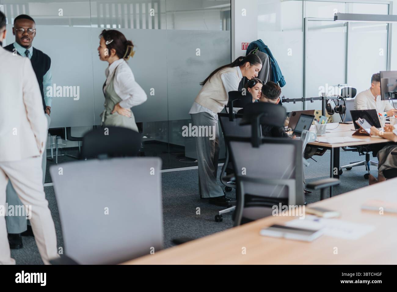 Group of employees working together in an open office space, promoting teamwork and collaboration. Stock Photo