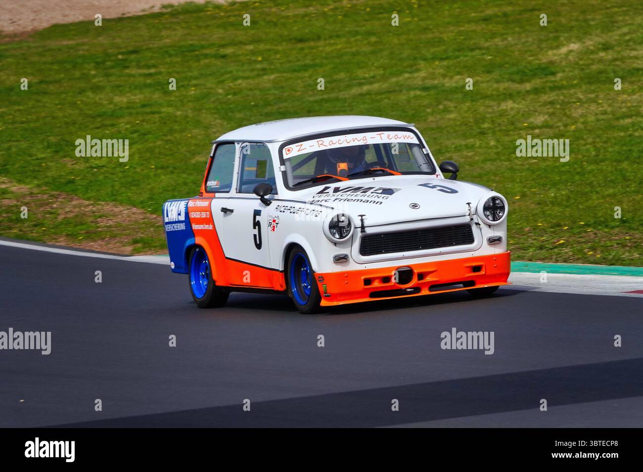 A white and orange Trabant 601 with racing number 5 competing on the Most Circuit (Czech Republic) during a historic motorsport event. The car has bee Stock Photo