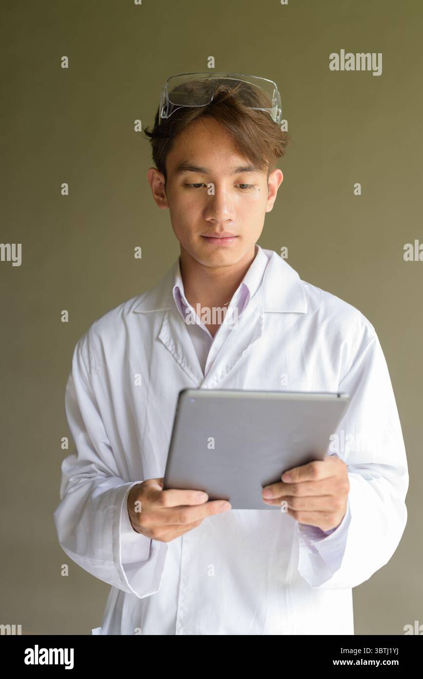 Young Asian scientist student researcher wearing lab coat working with digital tablet computer Stock Photo