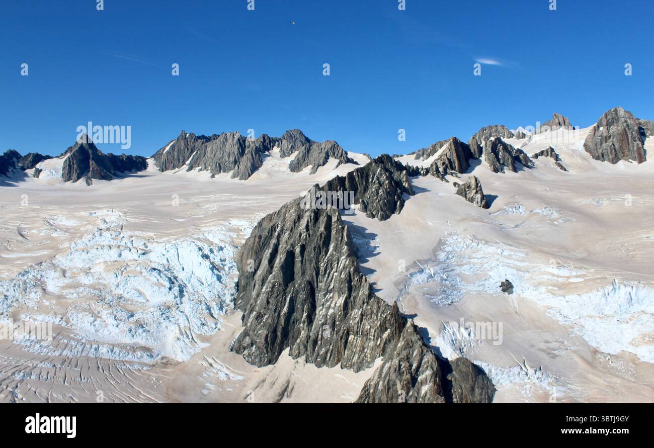 Aerial view of rugged mountain ridge and vast glacier with deep blue ...