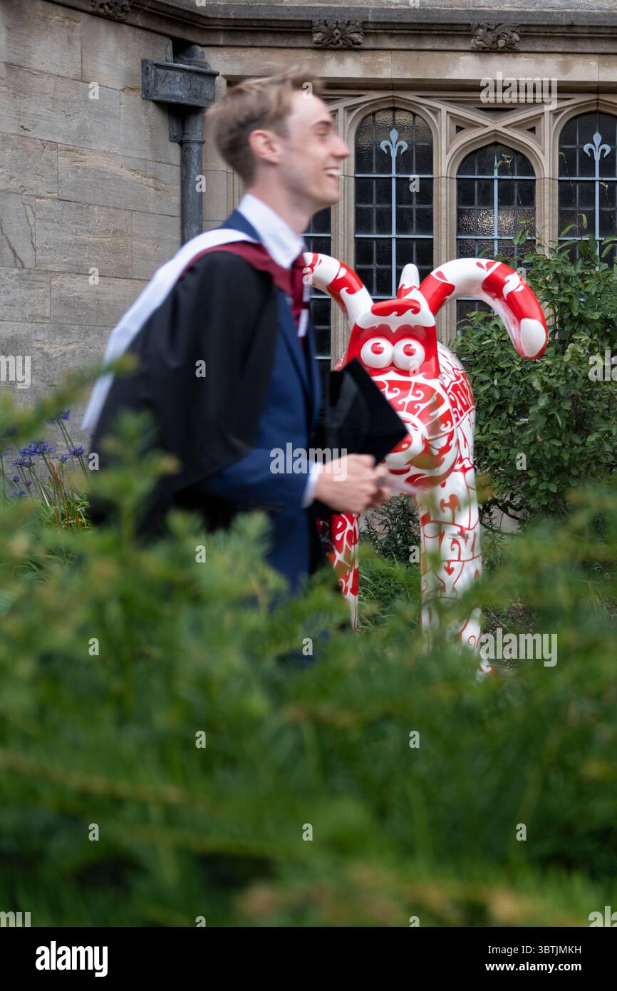 Bristol UK. A University graduate is shown walking past bristol university to a graduation ceremony. He's wearing a Academic regalia and smiling Stock Photo
