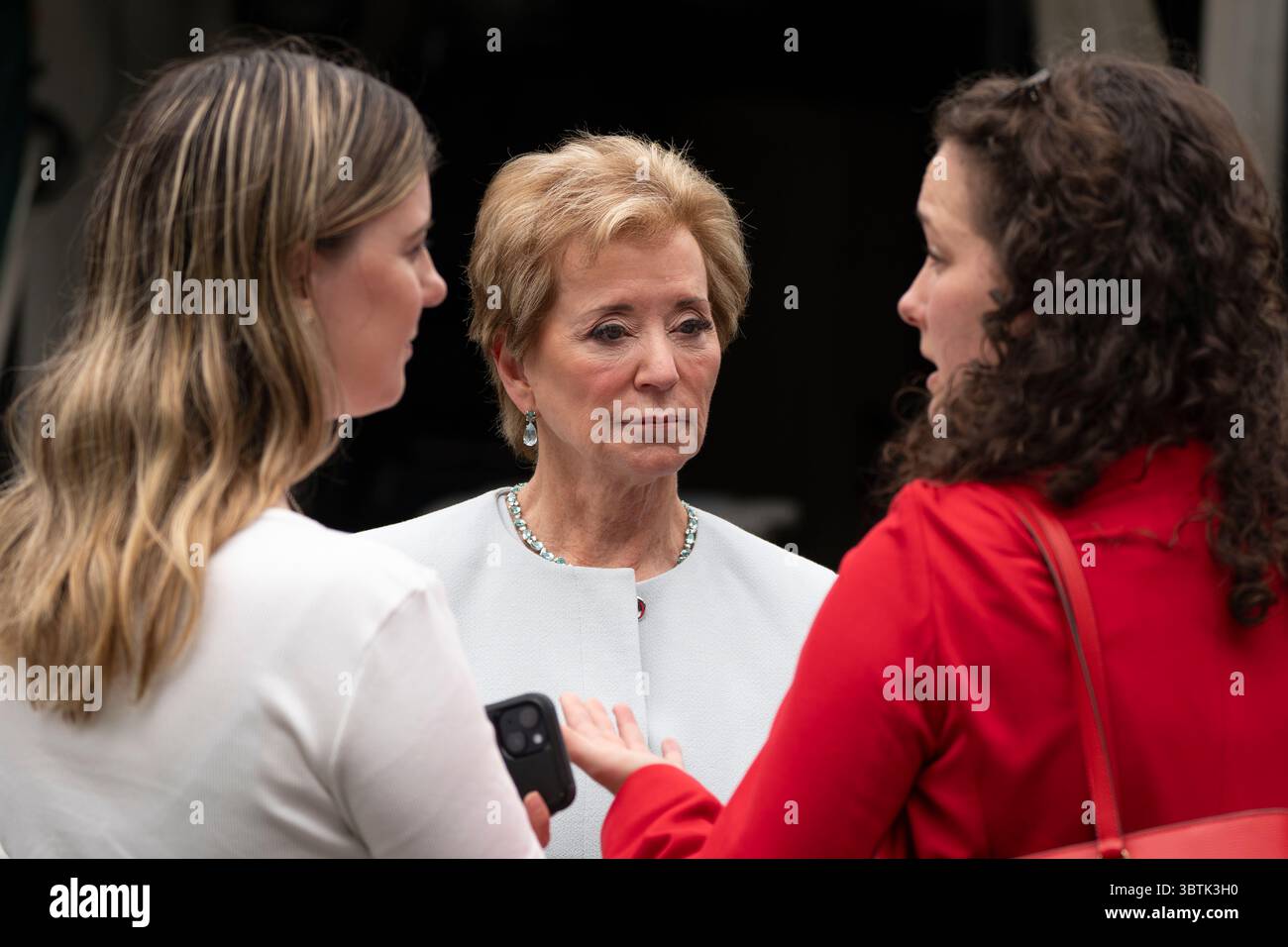 Education Secretary Linda McMahon, talks to her staff as they wait on