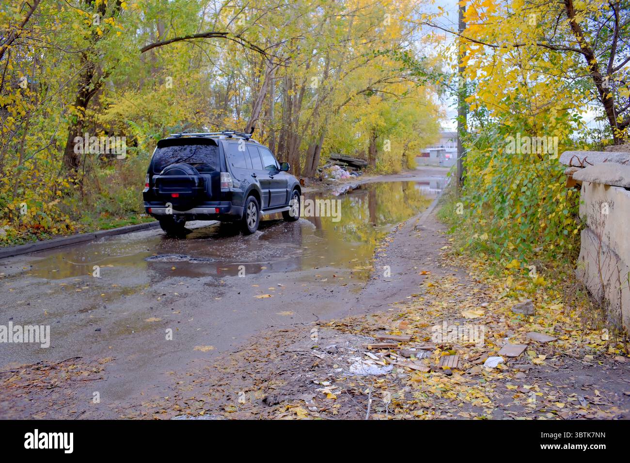 Damaged asphalt road surface on an autumn rainy day close-up, road repair is needed Stock Photo