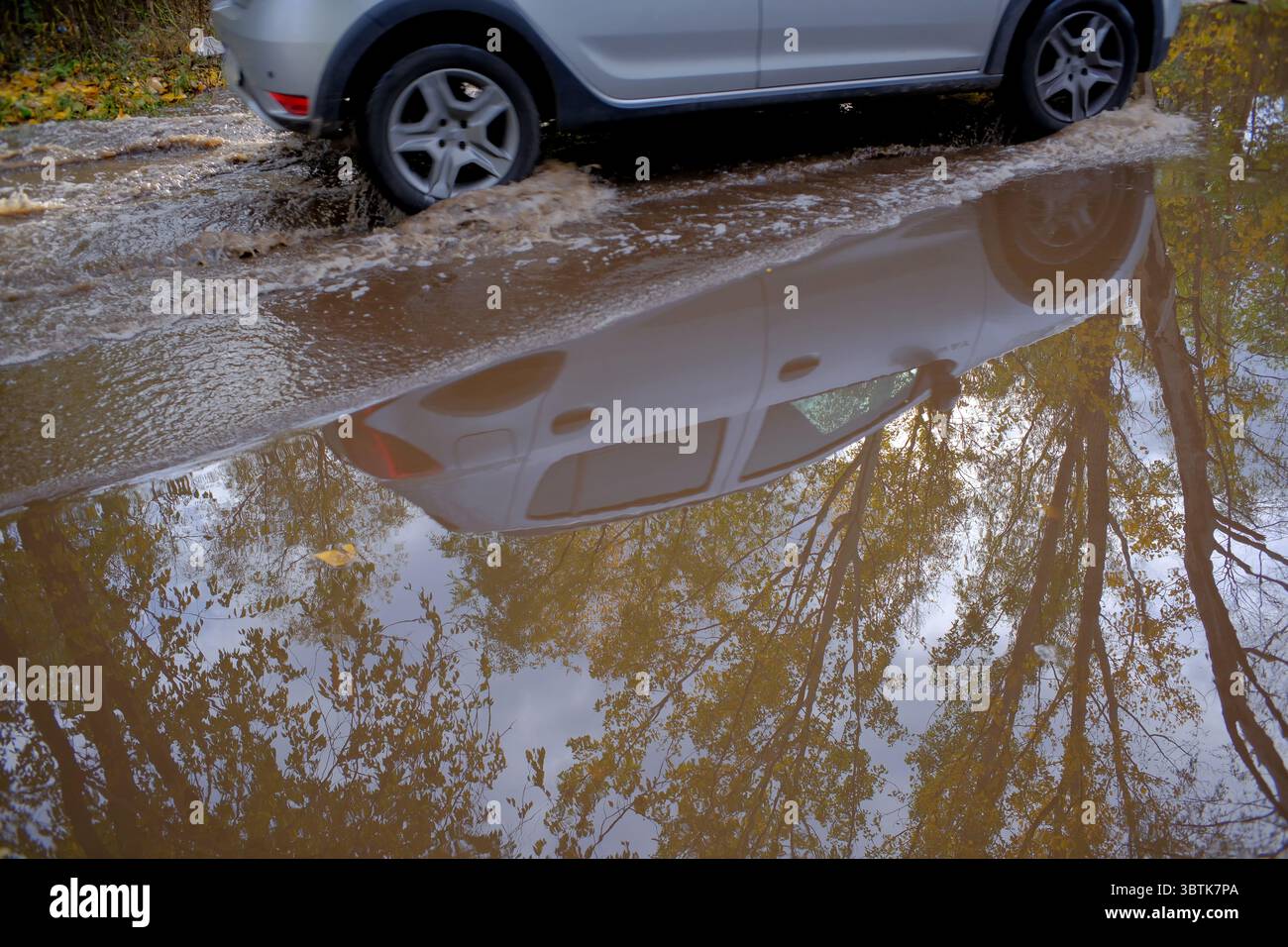 Damaged asphalt road surface on an autumn rainy day close-up, road repair is needed Stock Photo