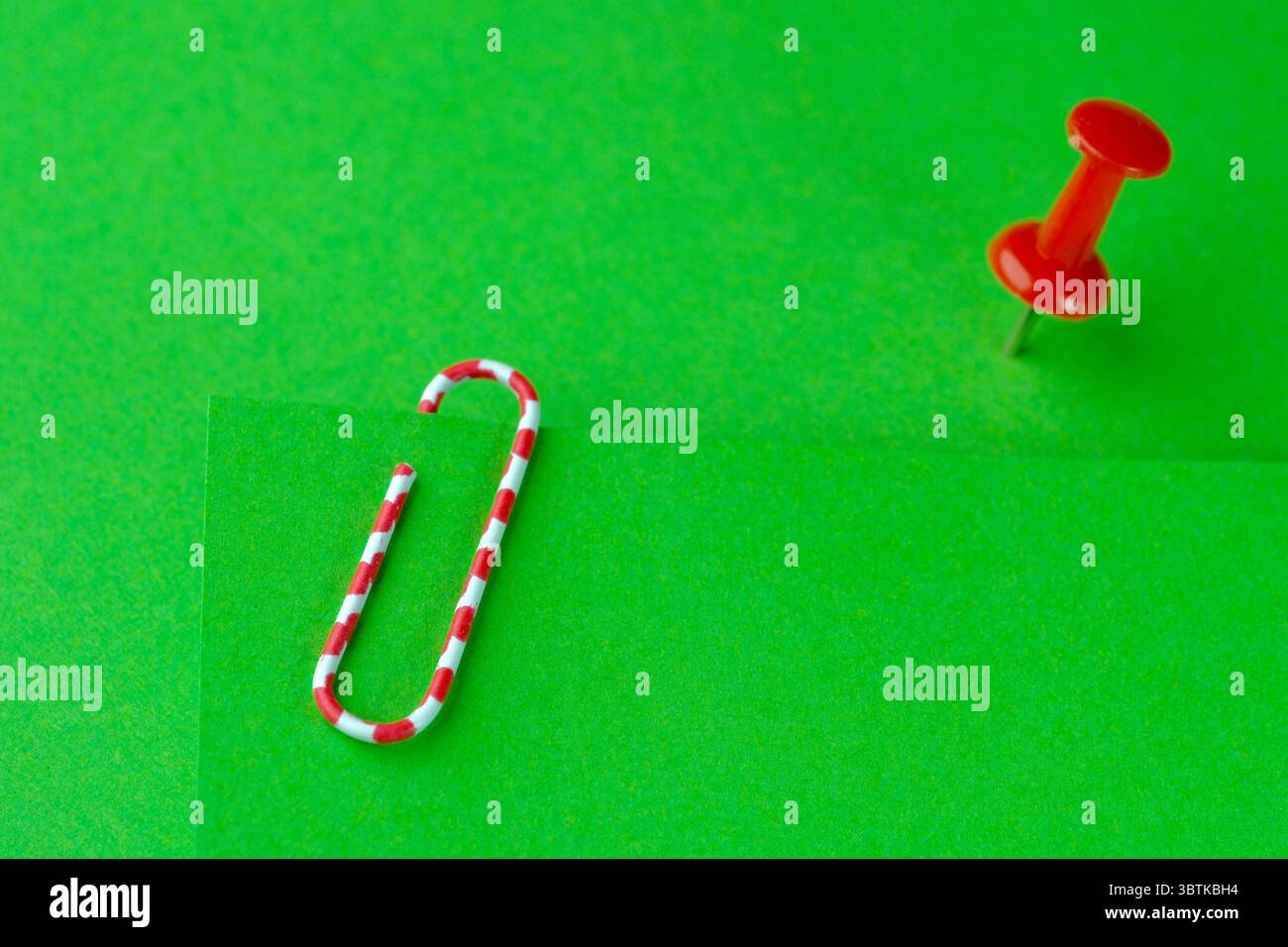 Red paperclip and red button on green blank sheets Stock Photo