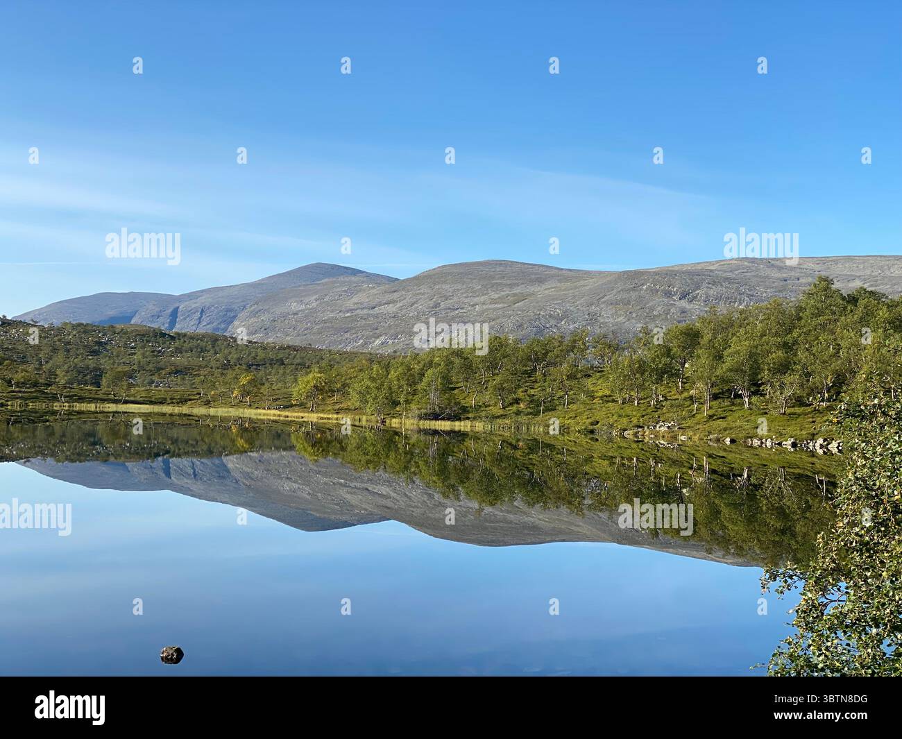 Stunning scenery of a lake reflecting mountains and a bright, clear sky. - Smartphone Captured Stock Image