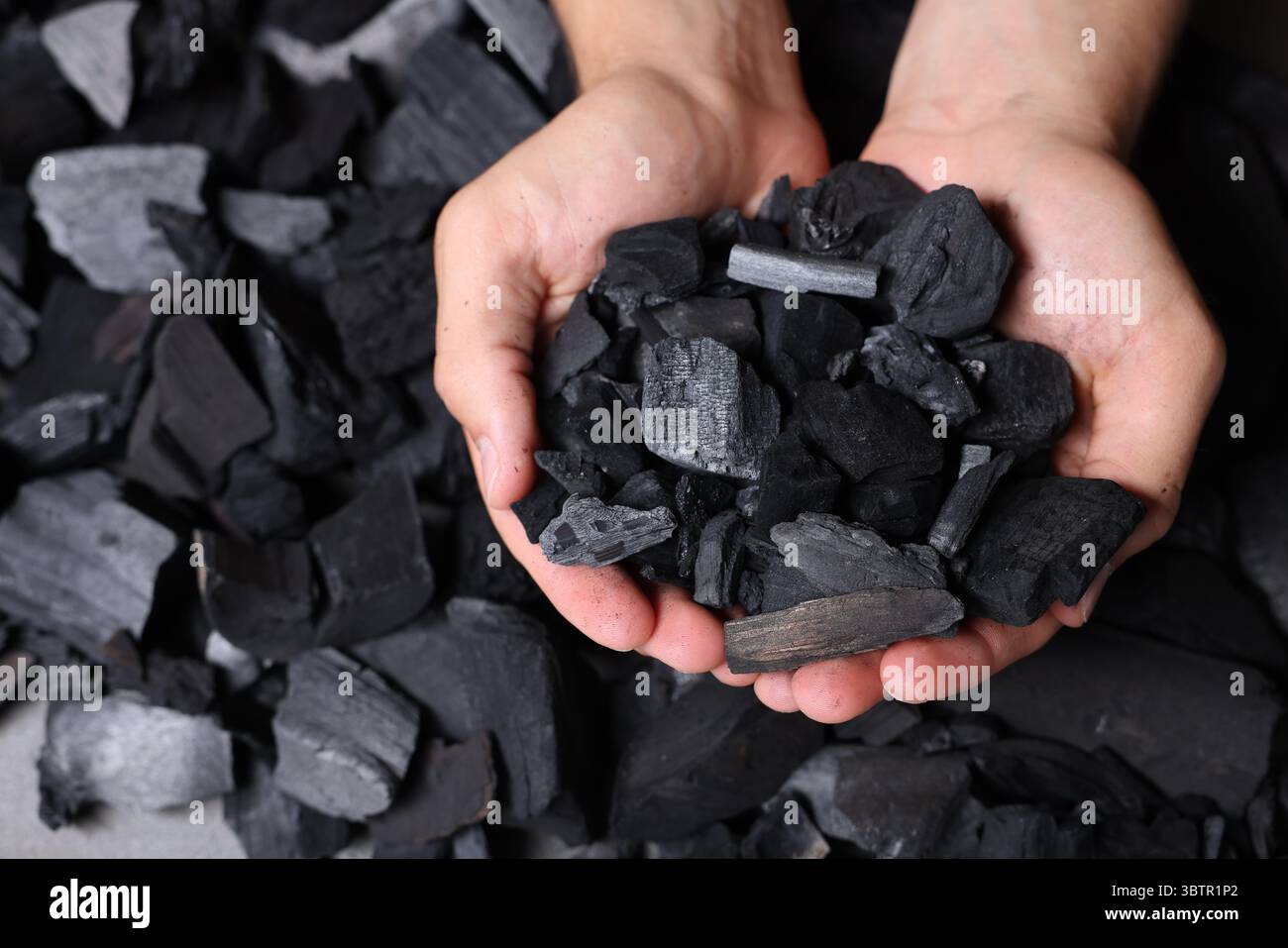 Man with black coals over pile, top view Stock Photo