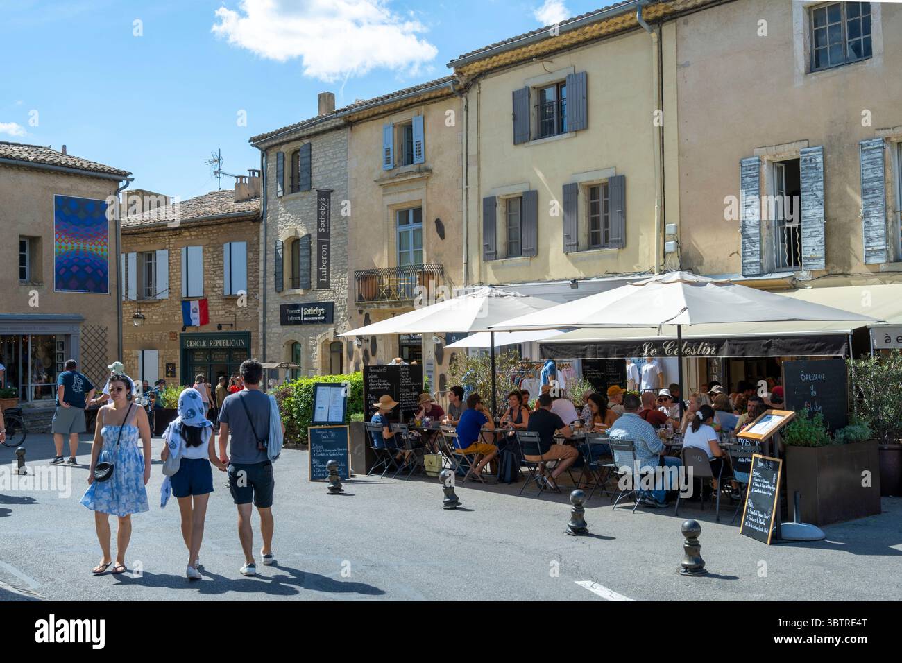 Street scene and diners at Le Celestin restaurant in town square of Gordes in Luberon part of Provence, Vaucluse department, Southern France Stock Photo