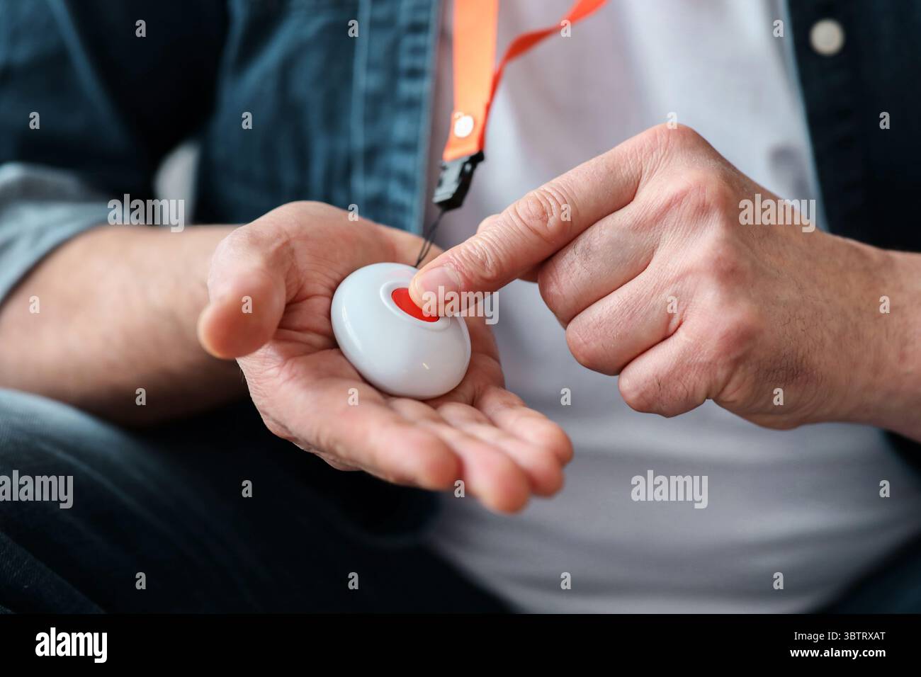 Hand pushing panic button on emergency equipment for elderly people Stock Photo