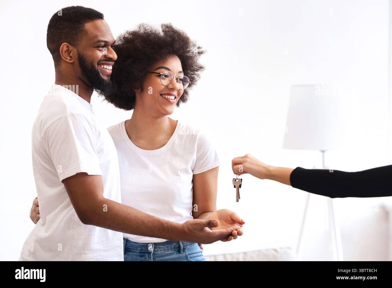 Real Estate Agent Giving House Key To Black Couple Indoors Stock Photo ...