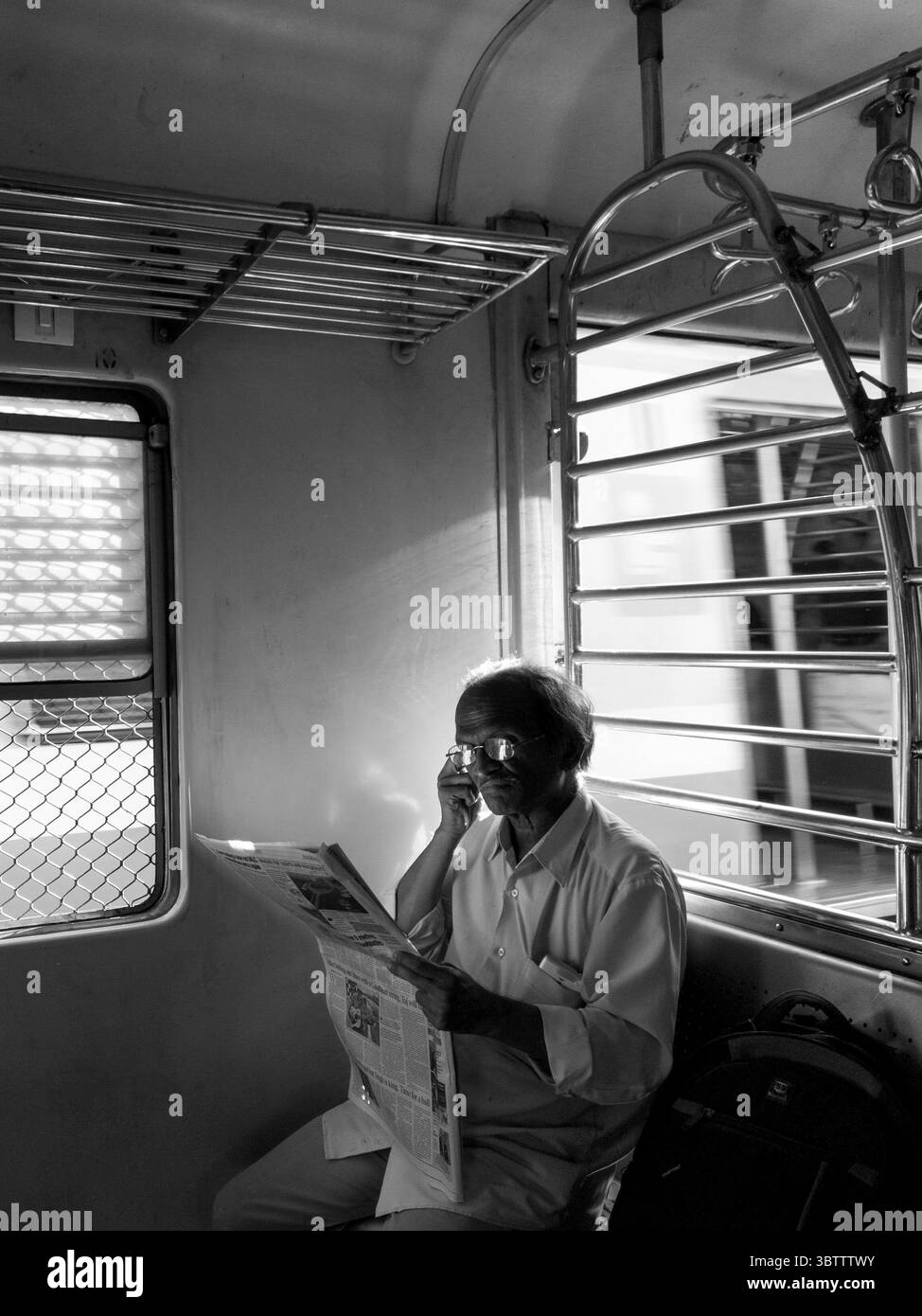 Man reading a newspaper inside a Mumbai local train, India. - Smartphone Captured Stock Image