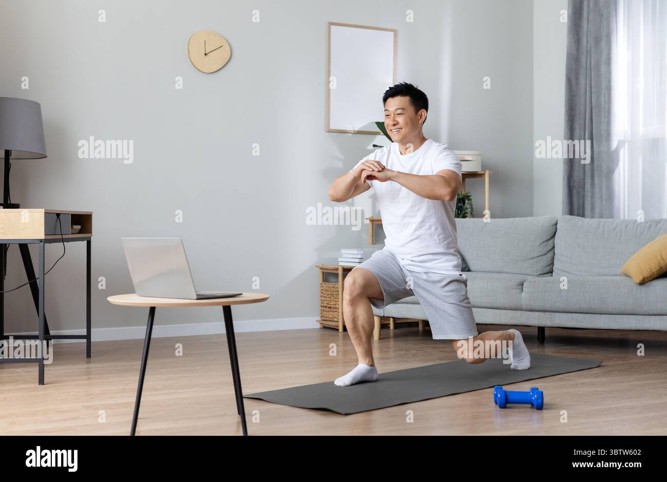 Motivated asian man exercising at home, using laptop Stock Photo