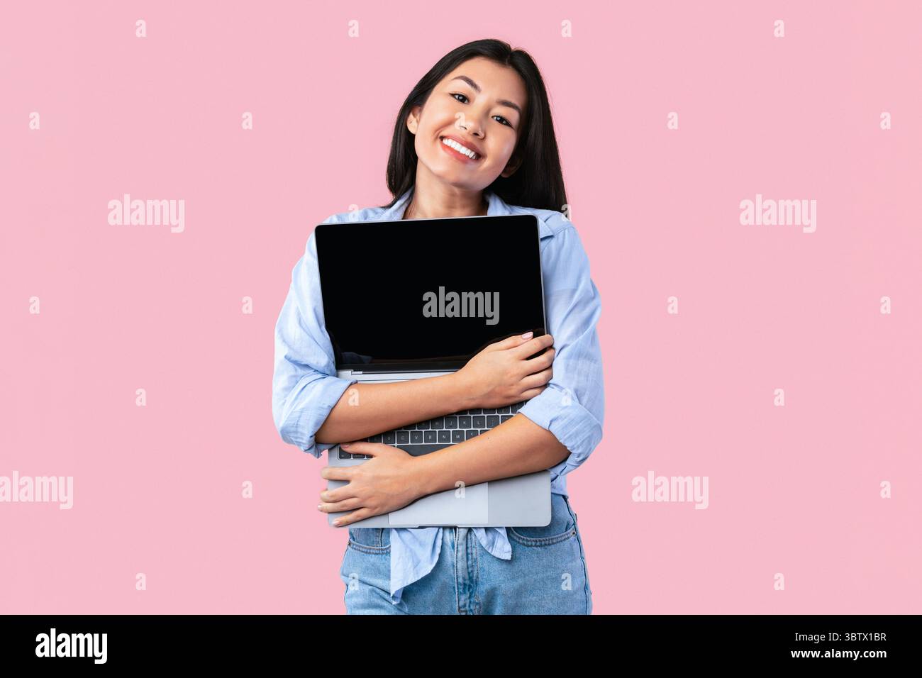 Excited asian woman hugging personal computer at studio Stock Photo