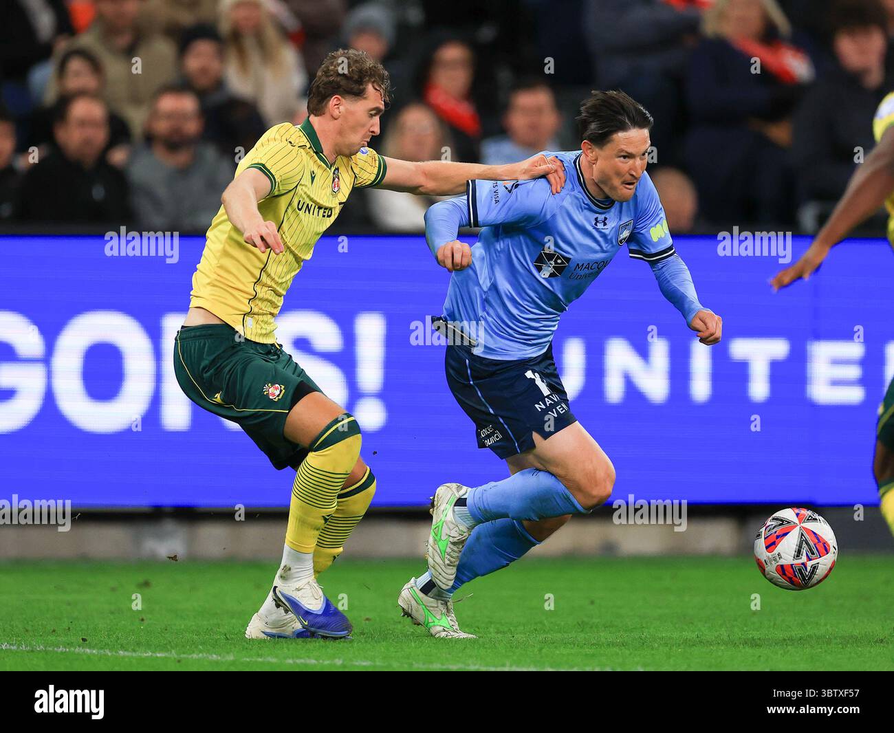 Lewis Brunt (L) of Wrexham AFC tries to block Joe Lolley of Sydney FC ...