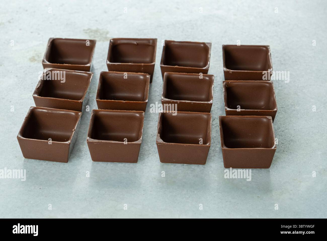 Square-shaped milk chocolate shells ready to be filled Stock Photo - Alamy