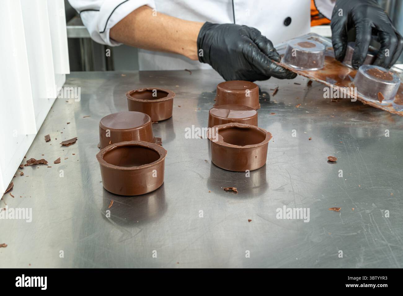 Circular chocolate shells on the counter with a worker in the ...