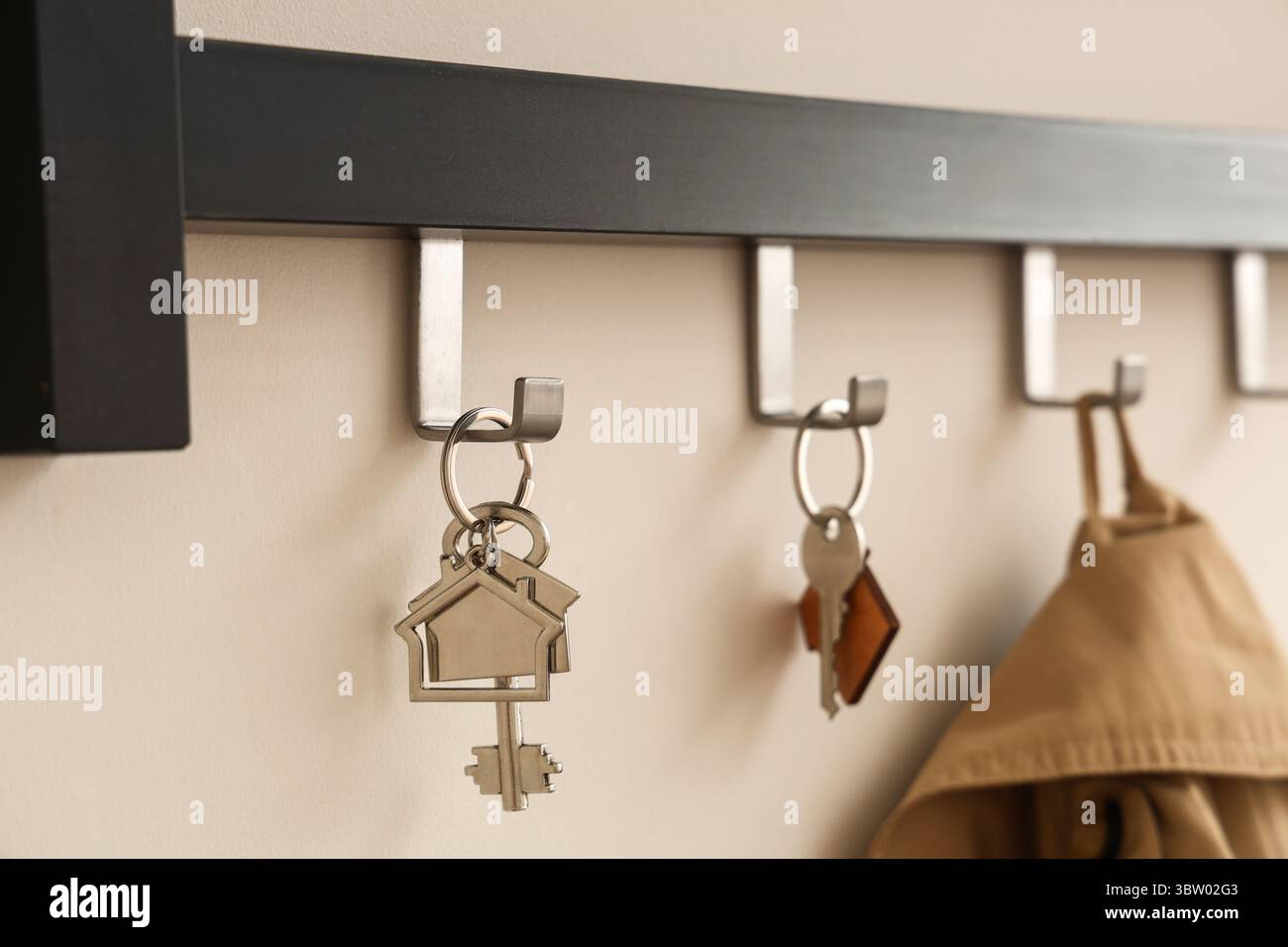 Rack with keys from house on light wall, closeup Stock Photo
