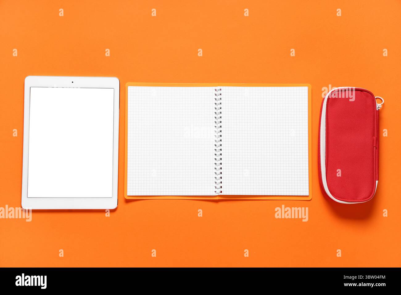 Composition with modern tablet computer and school supplies on orange background Stock Photo