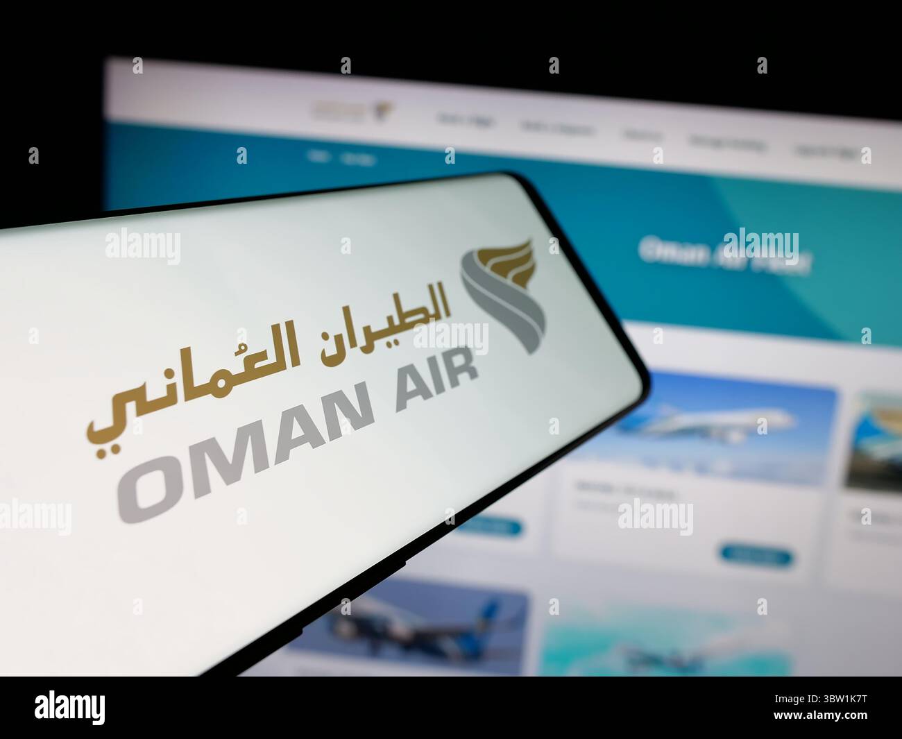 In this photo illustration, a smartphone with the logo of airline company Oman Air is seen on screen in front of website. Stock Photo