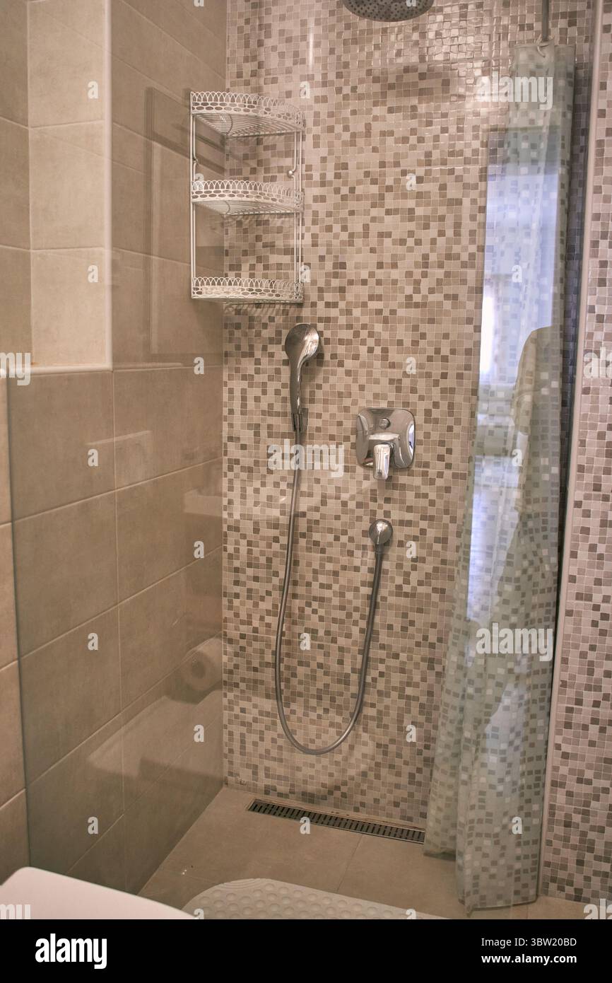 A modern bathroom shower featuring mosaic tiles with stainless steel fixtures. the sleek design combines elegance and functionality, enhancing any con Stock Photo