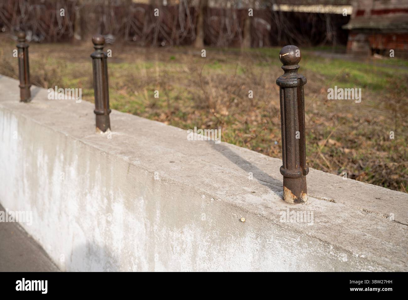 Cast iron posts in a row, on a concrete base, on the street, in a park ...