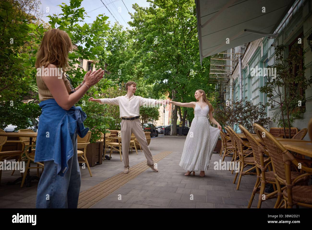 Romantic couple dancing on cozy outdoor terrace as woman in jeans claps ...