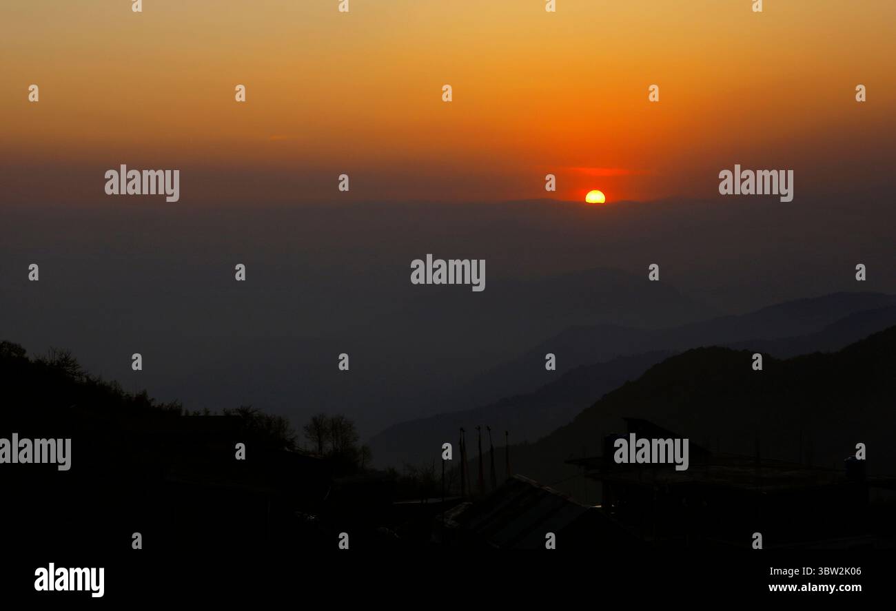 A breathtaking sunset paints the sky in warm hues over layered mountain ...