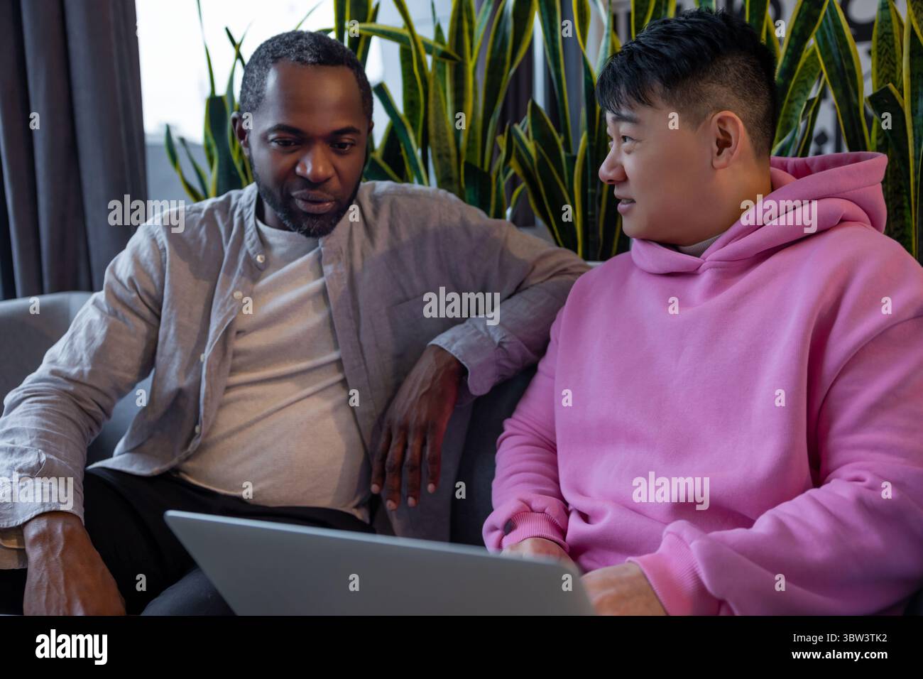Multiethnic business partners collaborating on laptop in informal workspace Stock Photo