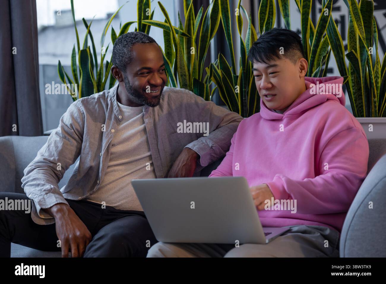 Multiethnic business partners collaborating on laptop in informal workspace Stock Photo