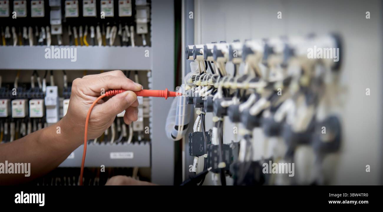 Electrical engineer tests the operation of the electric control cabinet ...