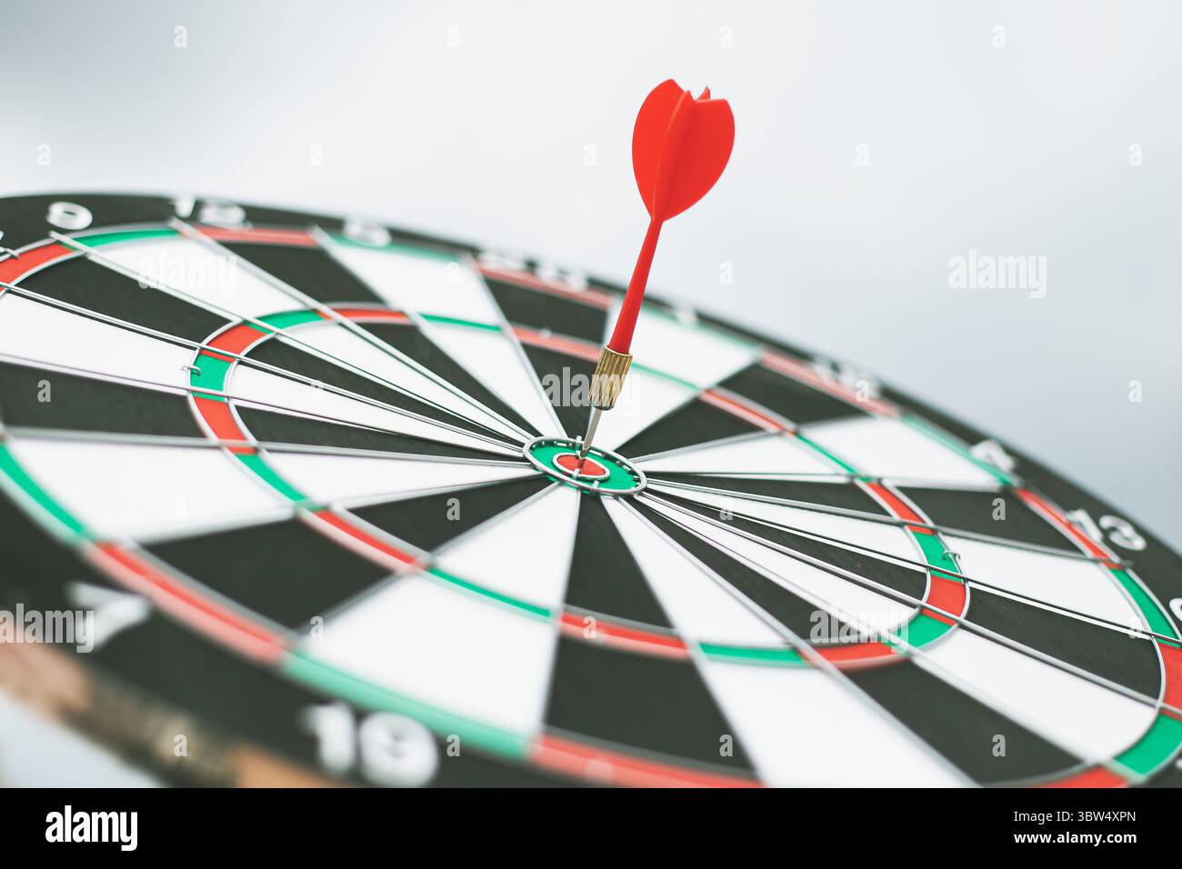 Dart arrow hitting in the target center of dartboard Stock Photo