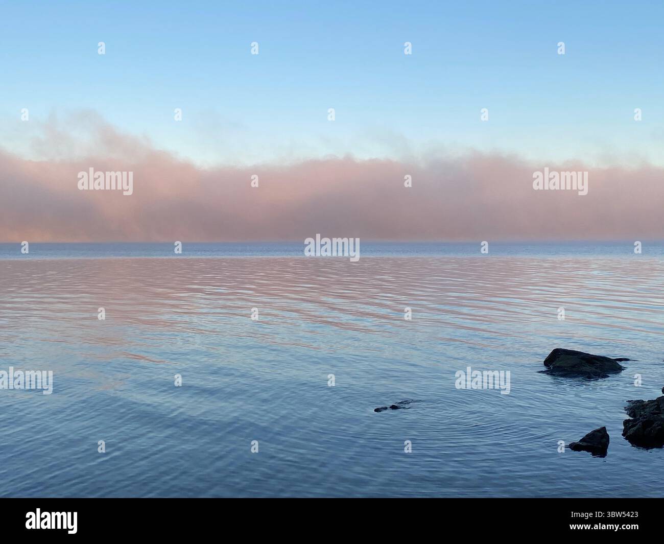 The water reflects the sky's colors at sunrise, creating a stunning mirrored effect. - Smartphone Captured Stock Image