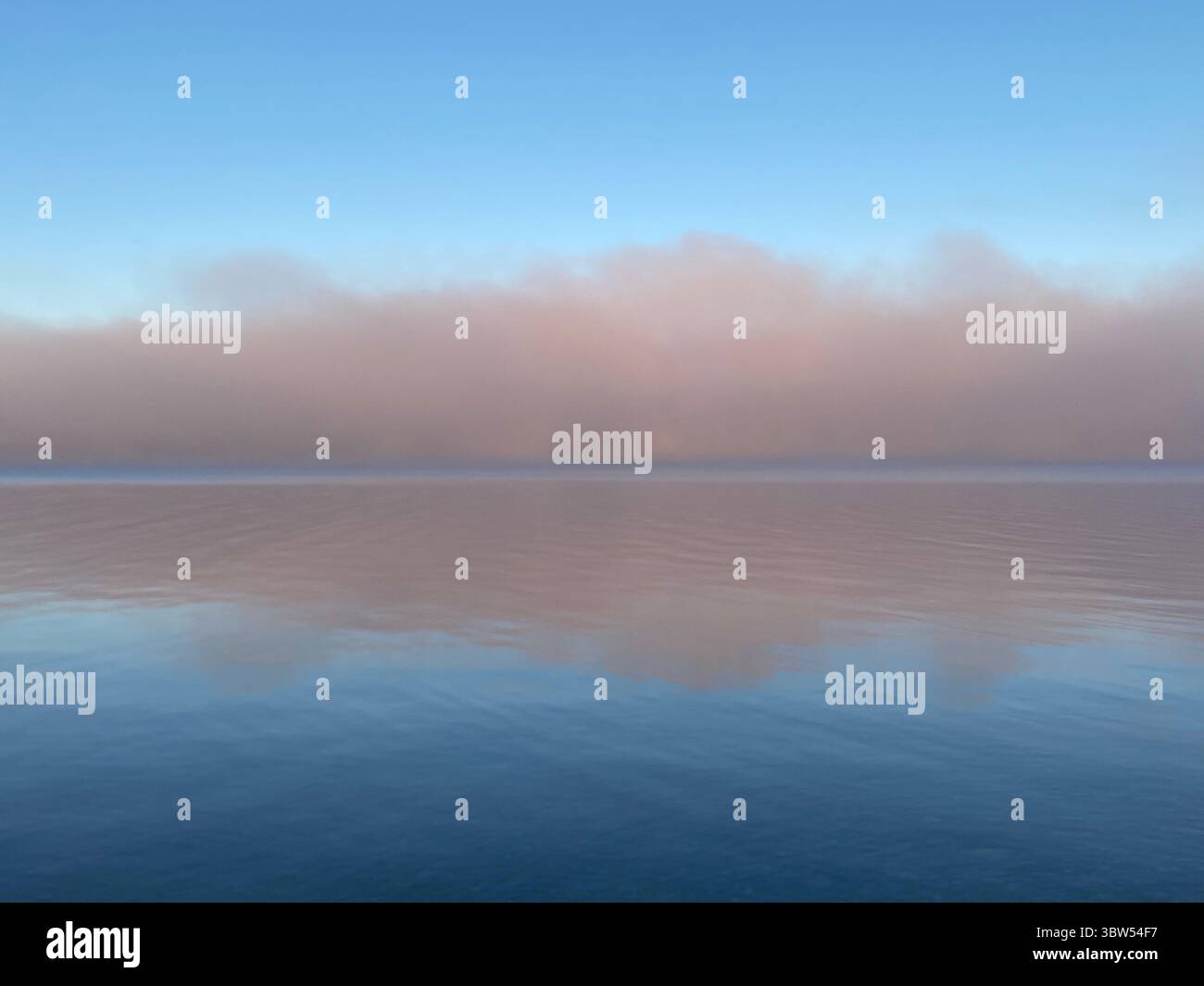 The water reflects the sky's colors at sunrise, creating a stunning mirrored effect. - Smartphone Captured Stock Image