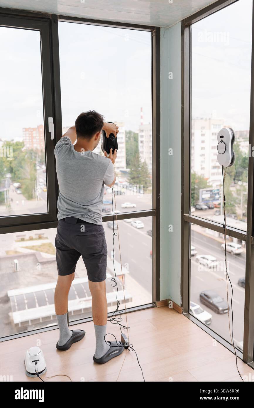 Rear view of housekeeper male using advanced robotic device for ...