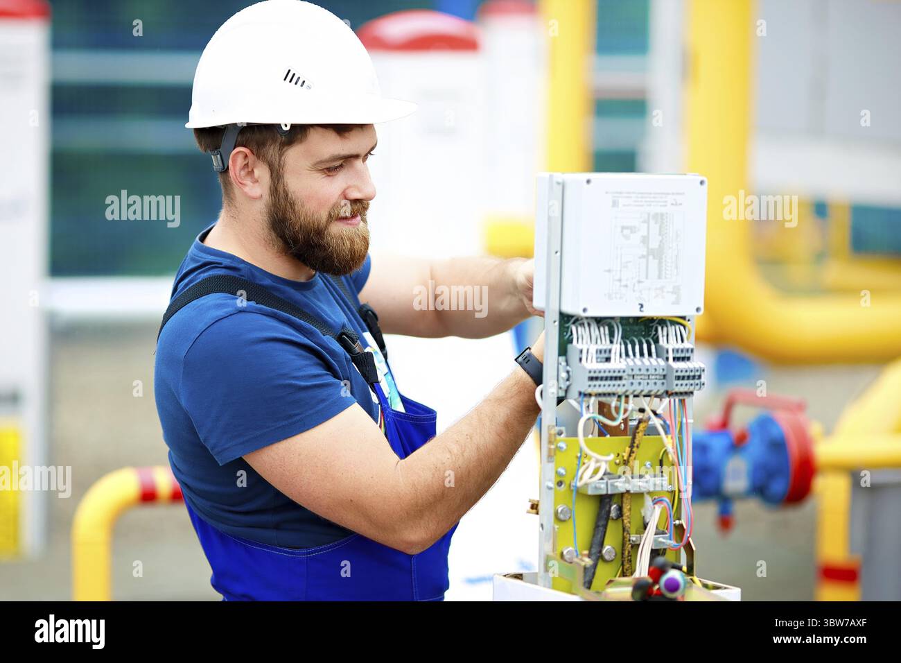 An engineer in a helmet and work clothes adjusts and inspects the ...