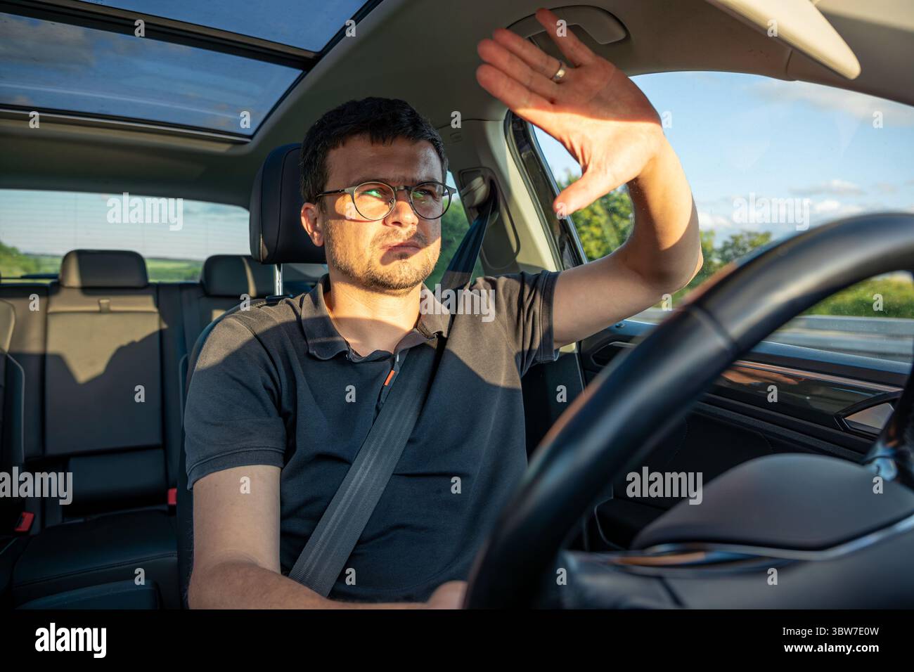 Driver shielding eyes. Sun glare in car. Highway journey Stock Photo ...