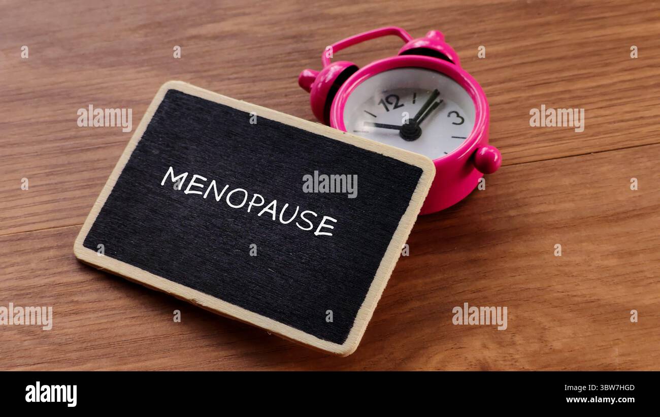 Menopause Concept with Pink Alarm Clock and Blackboard Stock Photo