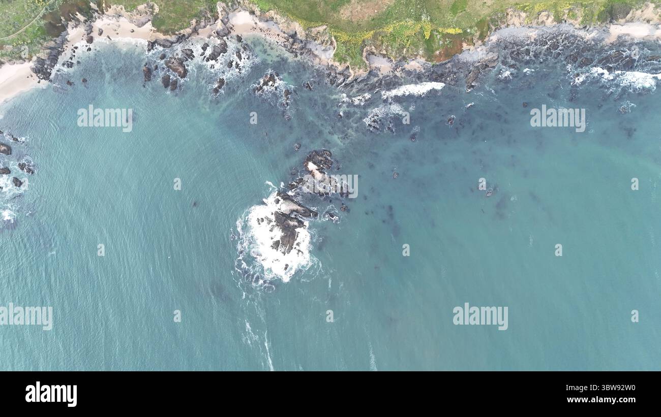 Aerial view of rocky shoreline and turquoise waters near Half Moon Bay, California — where waves crash into the rugged Pacific coast. Stock Photo