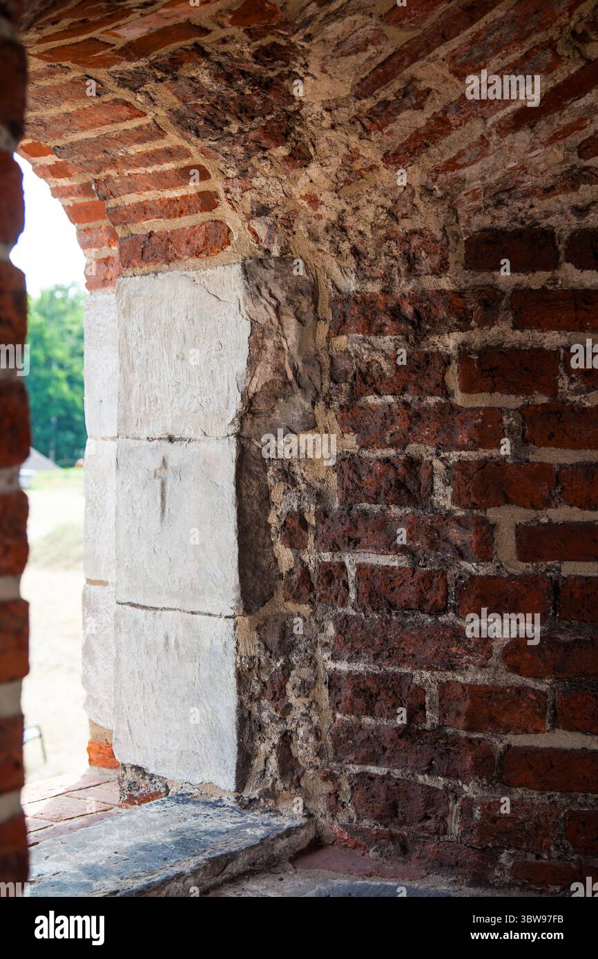 A stone-framed arched window in a centuries-old red brick stronghold Stock Photo