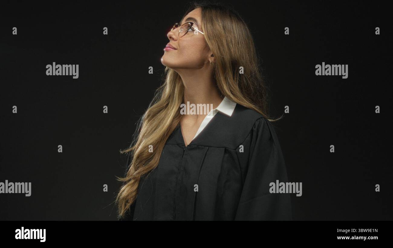 Woman judge wearing glasses and black robe tilts chin upward while ...