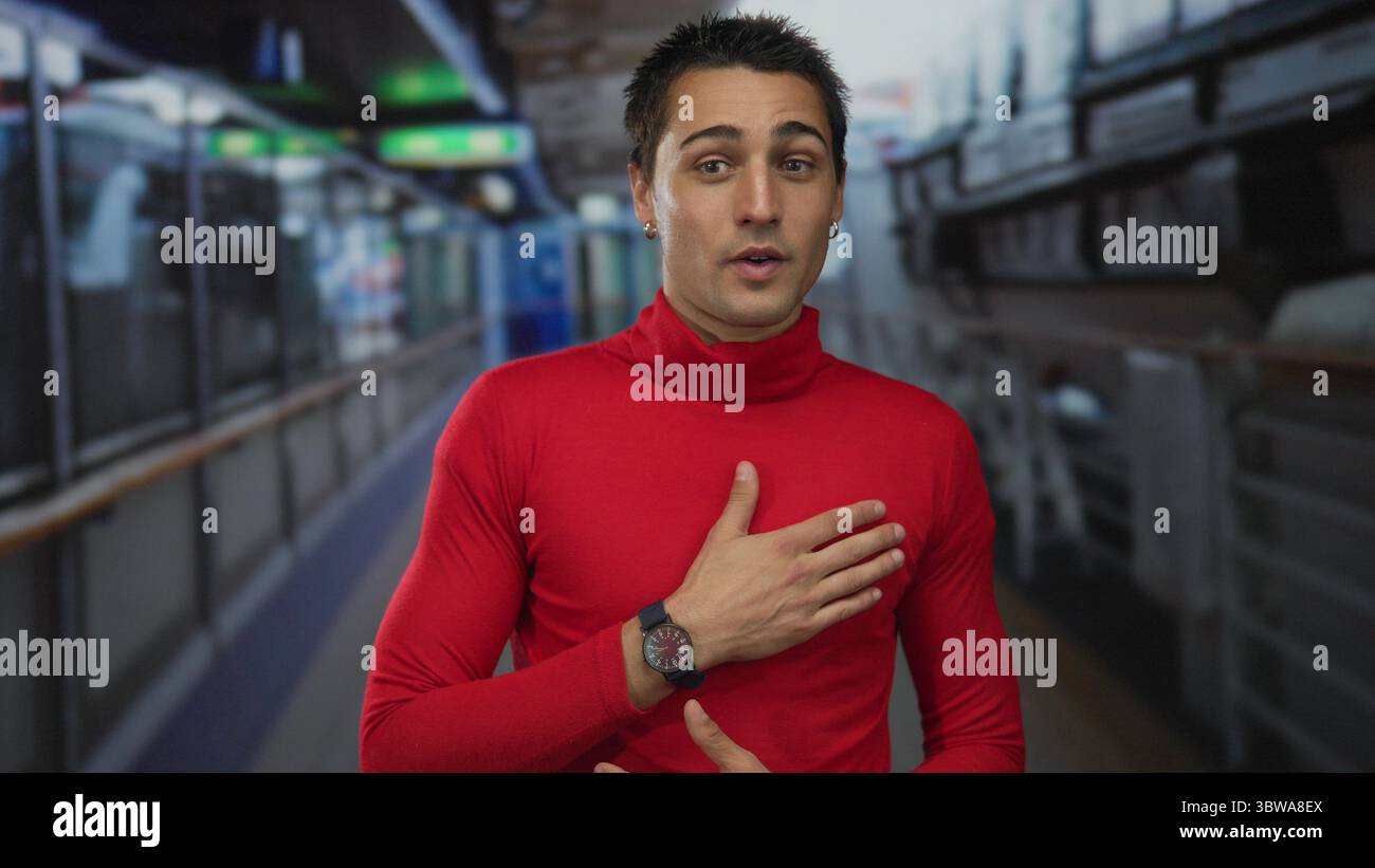 Young man wearing a red shirt gestures expressively onboard a cruise ship, with blurred railings and nautical equipment in the background, capturing a Stock Photo
