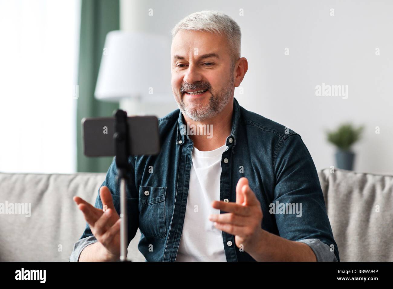 Smiling senior man vlogger broadcasting from home Stock Photo