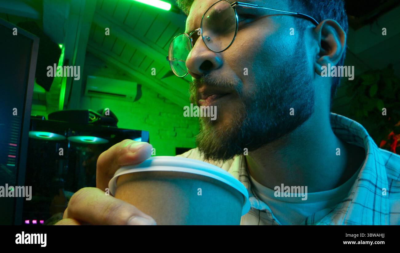 Pensive Caucasian man professional software engineer guy male coder programmer crypto specialist drinking coffee workplace looking computer thinking Stock Photo