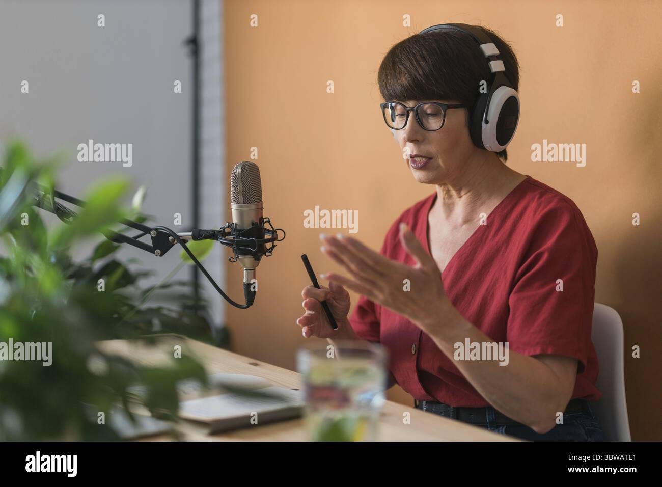 Middle-aged woman radio host making podcast recording for online show - broadcast and dj concept Stock Photo