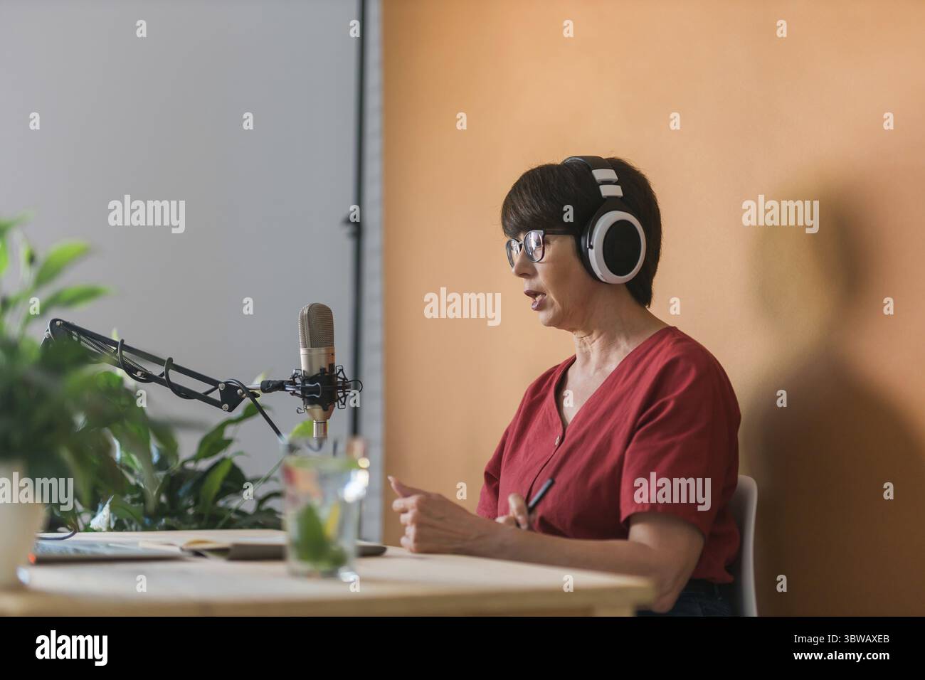 Portraet der reifen Frau mit Kopfhoerer und Gespraech im Online-Radio-Sender - Podcast und Broadcast-Konzept Stock Photo