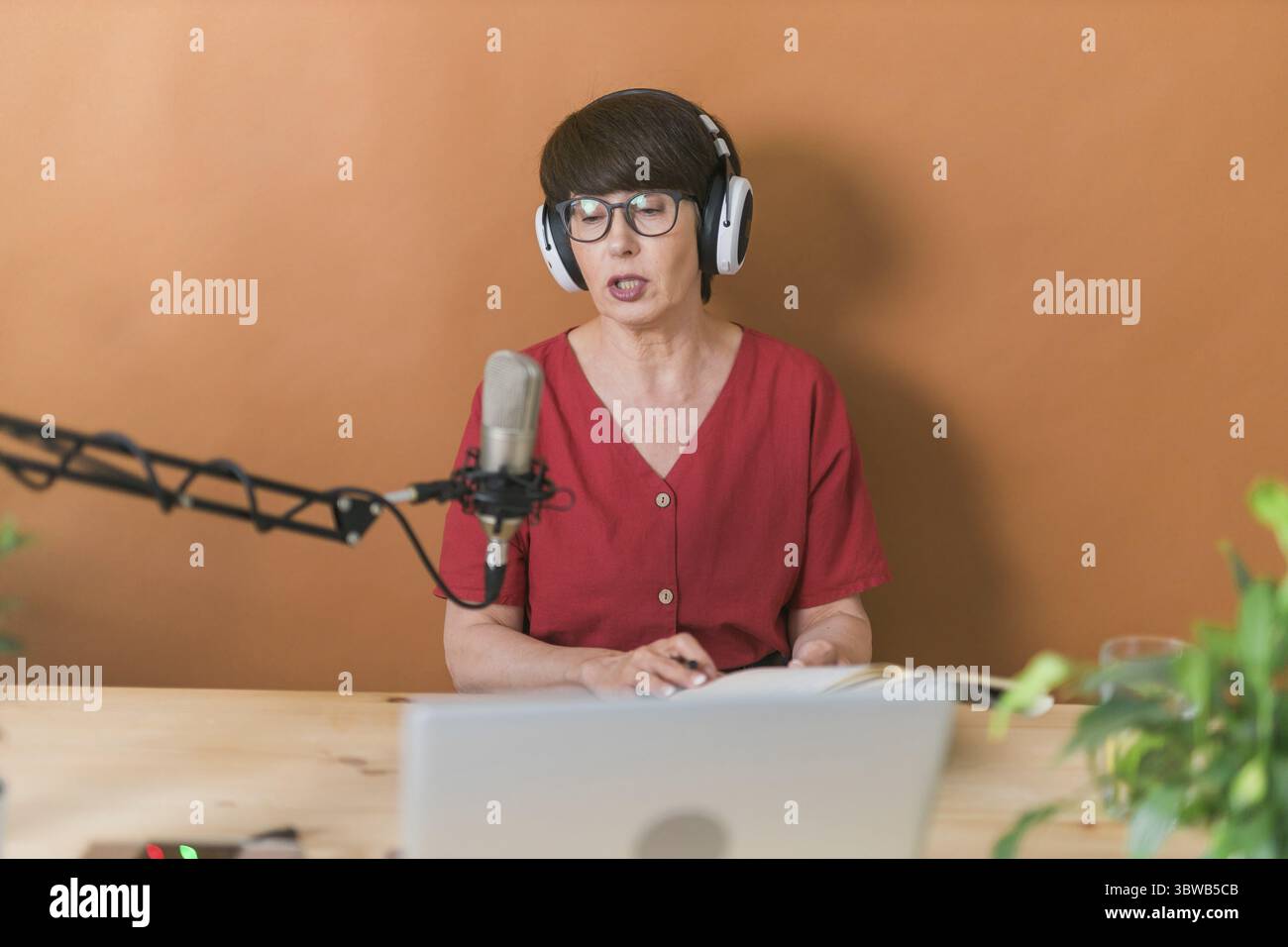 Portrait of mature woman wearing headphones and talking at online radio station - podcast and broadcast concept Stock Photo