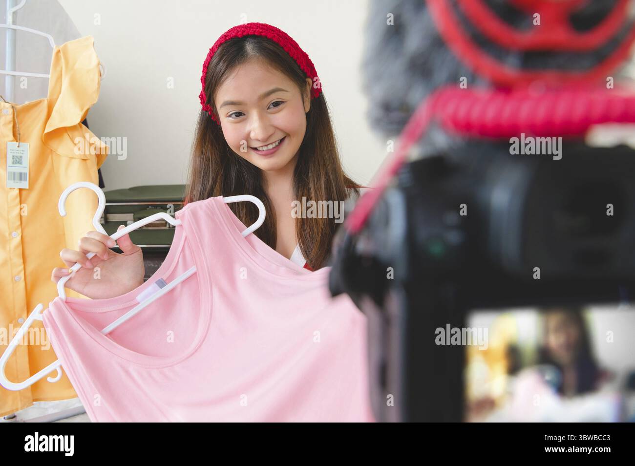Beauty young Asian Vlogger blogger interview with professional DSLR digital camera film video live. Woman coach trading review clothing product. Busin Stock Photo