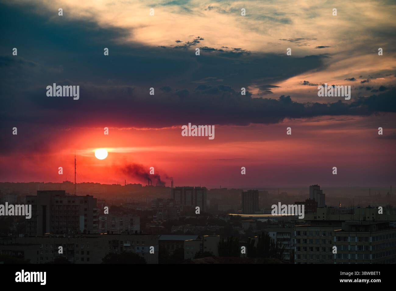 Colorful sunset with dramatic clouds over the skyline of Dnipro, Ukraine, photographed from a high vantage point. Silhouetted buildings. Wide angle vi Stock Photo