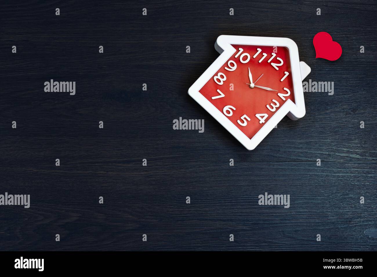 Home shape clock on floor background with red heart icon. Happy life ...