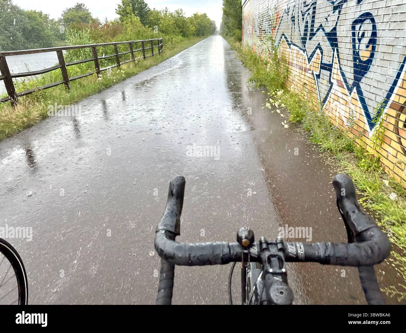 A road seen from the perspective of a cyclist on a bicycle on a rainy day with no hands on the bar - Smartphone Captured Stock Image